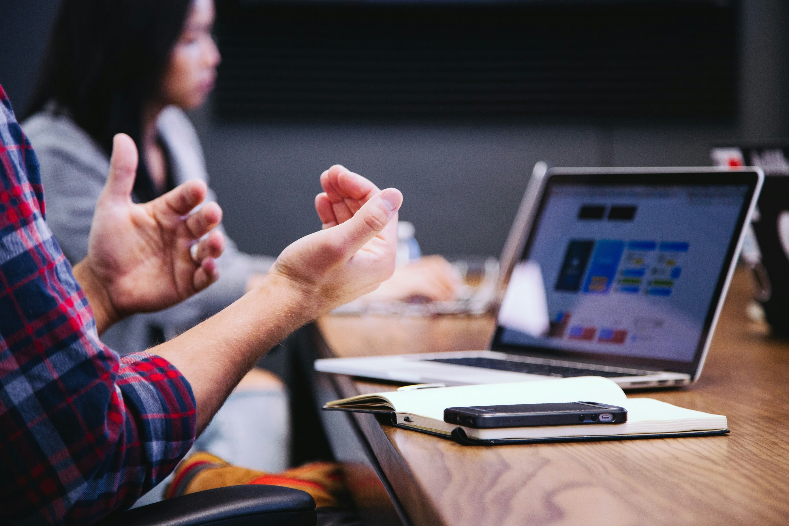 Third & Arch strategist gesturing while talking at a table with a laptop displaying charts for a AEC firm Website Design meeting.