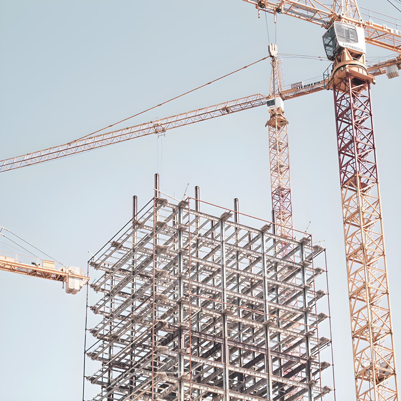 Daniel J. Keating Construction cranes over a building under construction.